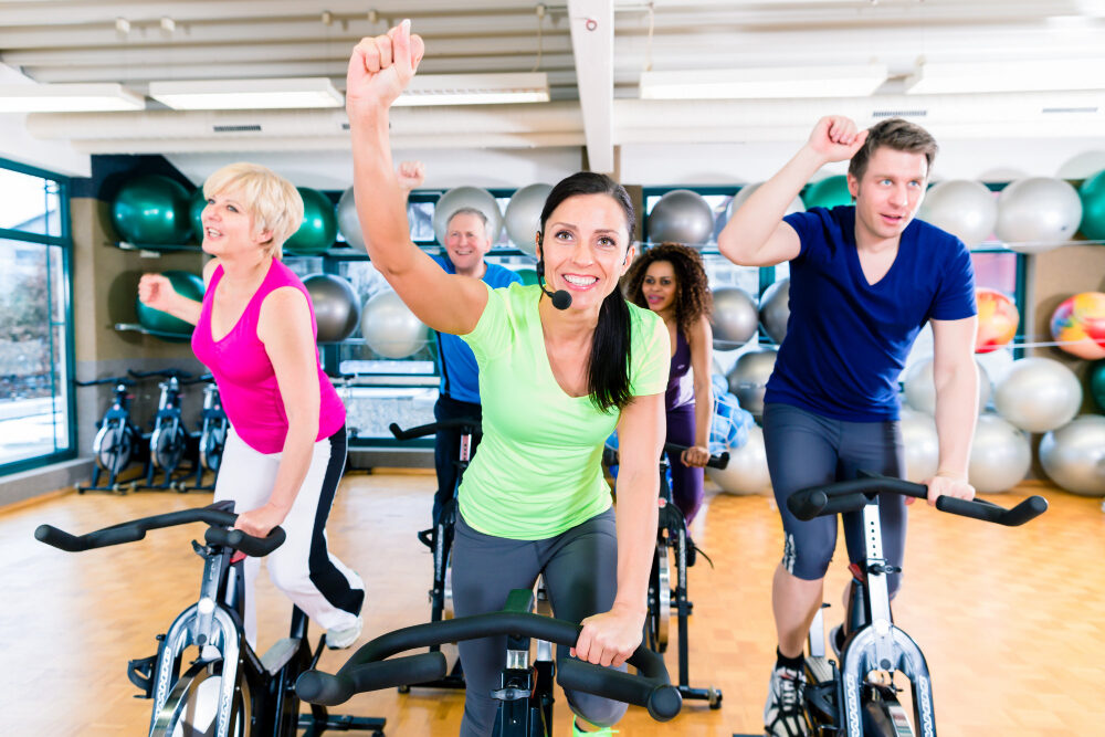 How Many Times Should I Spin Per Week. Group of men and women spinning on fitness bikes in gym